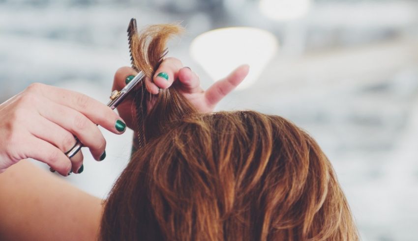 A woman is getting her hair cut by a pair of scissors.