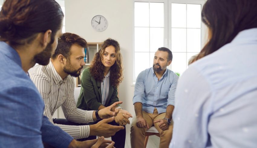 A group of people sitting in a circle talking to each other.