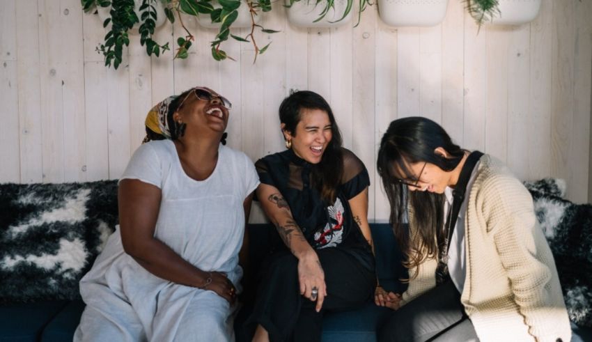Three women laughing on a couch.