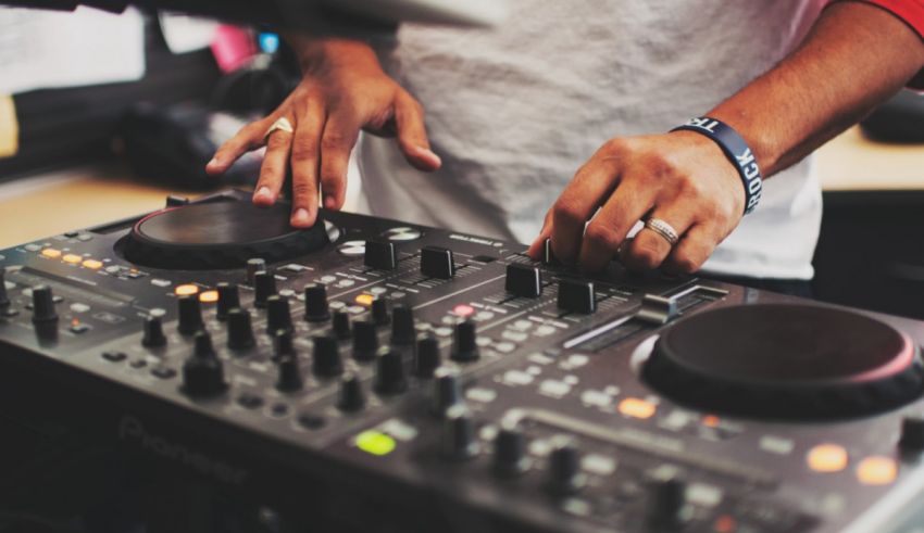 A dj is mixing music on a dj mixer.