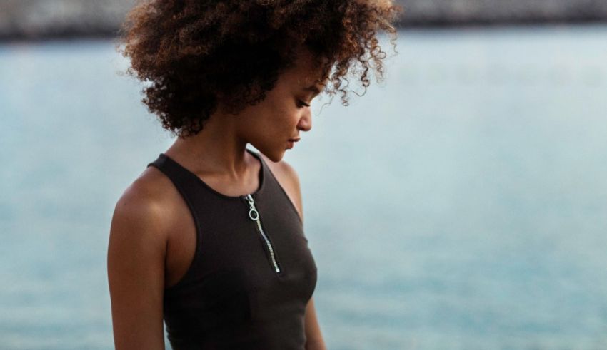 A woman with afro hair standing by the water.