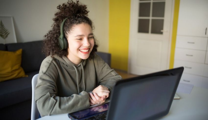 A young woman wearing headphones is using a laptop at home.