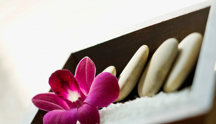 A flower and stones in a wooden box.