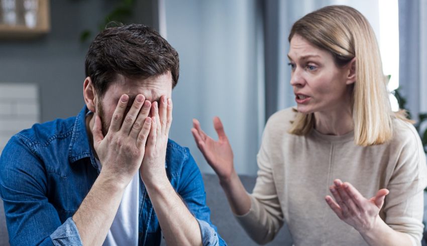 A man is covering his face while a woman is talking to him.