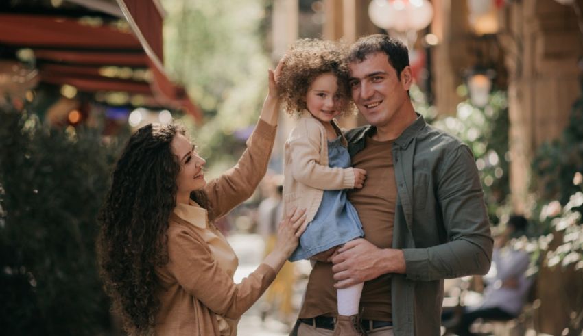 A family is holding a child in their arms while walking down the street.