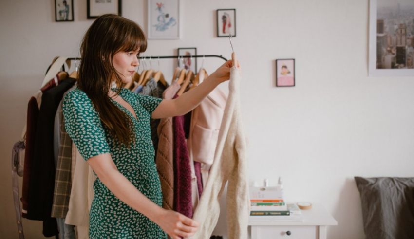 A woman is standing in front of a rack of clothes.