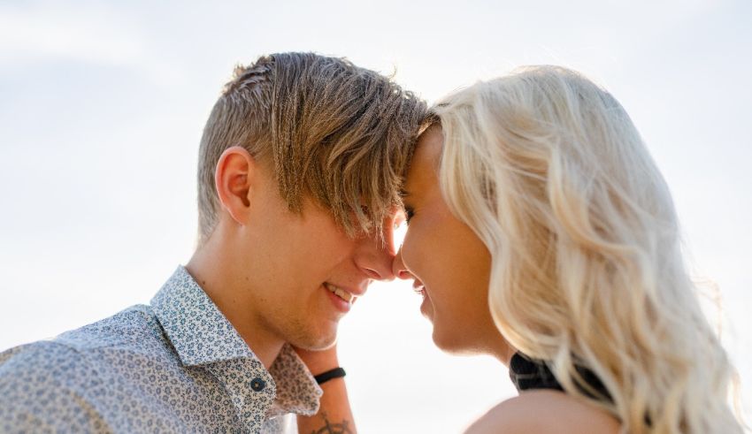 A man and a woman are embracing in front of the sun.