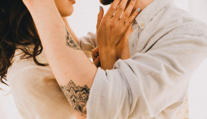 A man and woman hugging each other in front of a white wall.