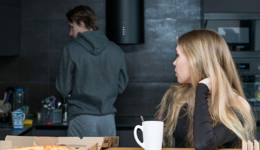 A woman is sitting at a table with a pizza box in front of her.