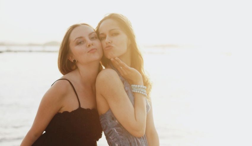 Two women posing for a photo by the water.