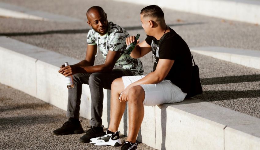 Two men sitting on a ledge talking to each other.