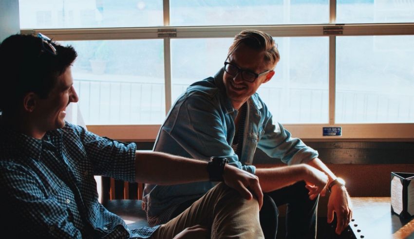 Two men sitting at a table talking to each other.
