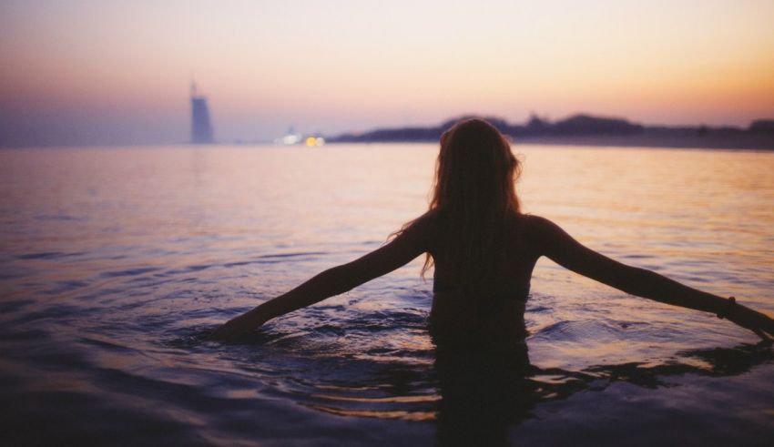A woman in the water with her arms outstretched.