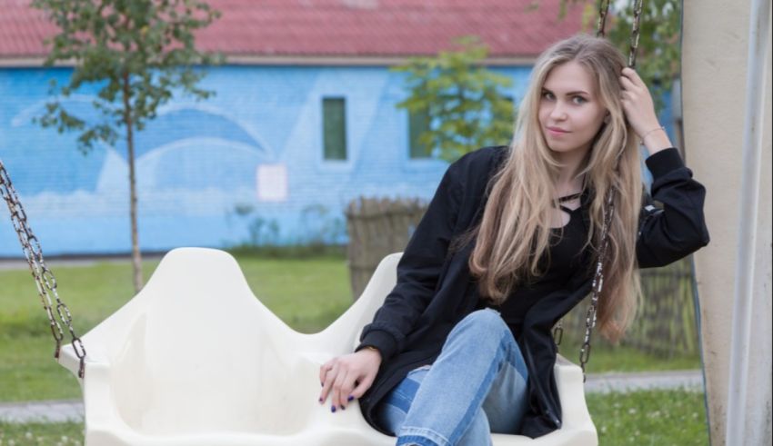 A young woman sitting on a swing in a park.