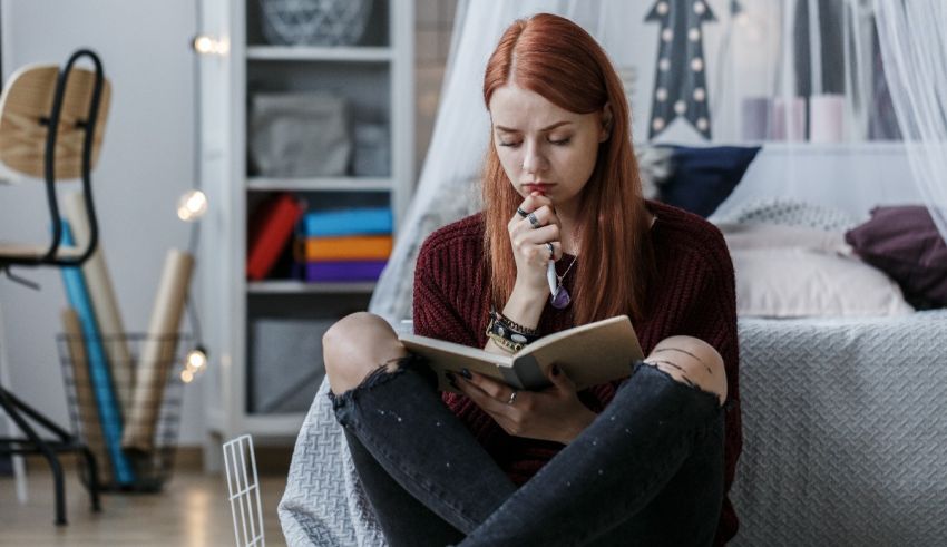 A young woman is sitting on the floor reading a book.