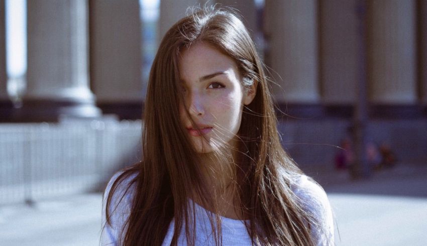 A young woman with long hair standing in front of a building.