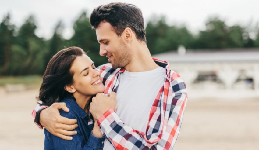 A man and woman hugging in front of a field.