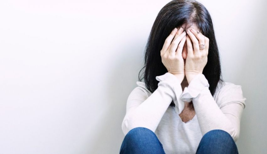 A woman covering her face with her hands.