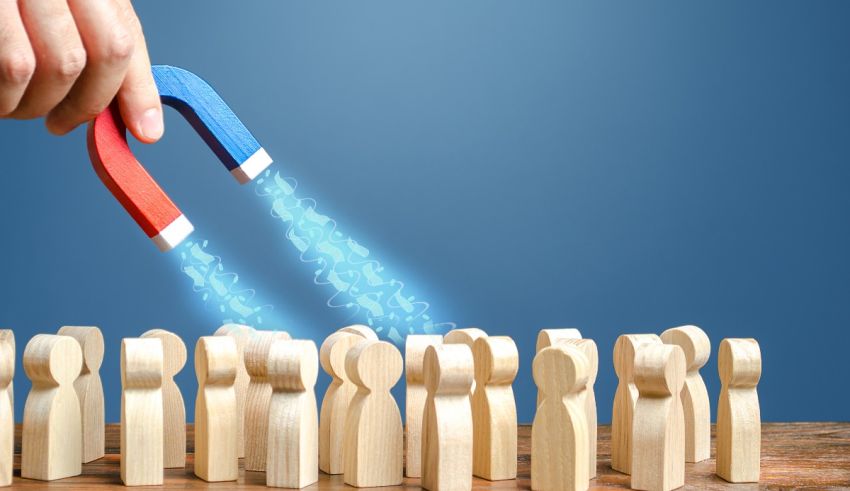 A person holding a magnet in front of a group of wooden people.