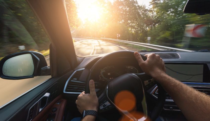 A man driving a car in the sun.