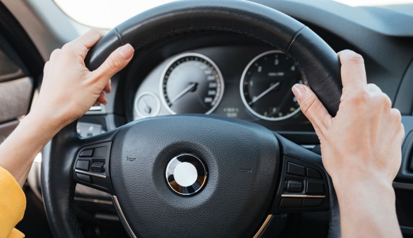 A woman is driving a car with her hands on the steering wheel.