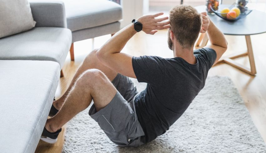 A man doing squats on the floor in front of a couch.