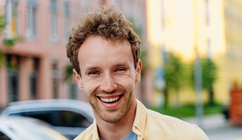 A smiling man in a yellow shirt standing in a city.