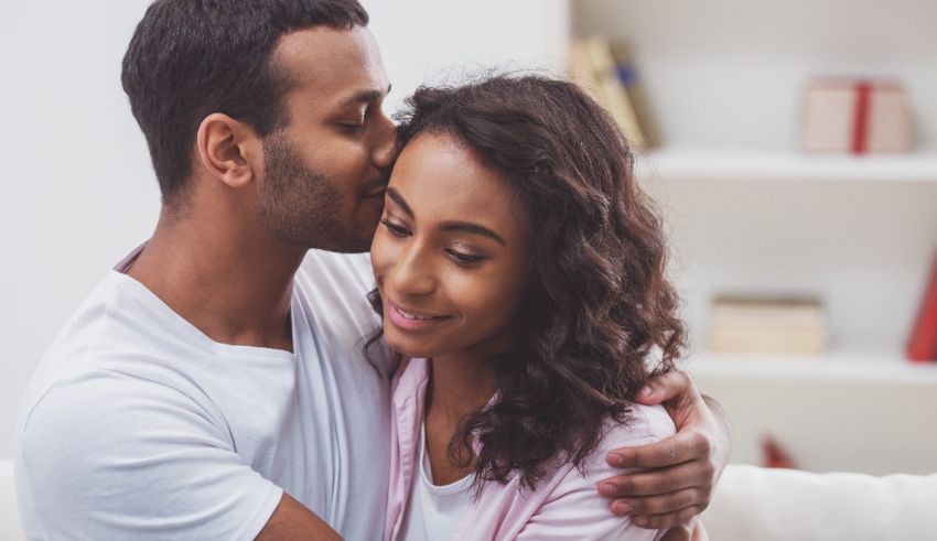 A man and woman hugging while sitting on the couch.