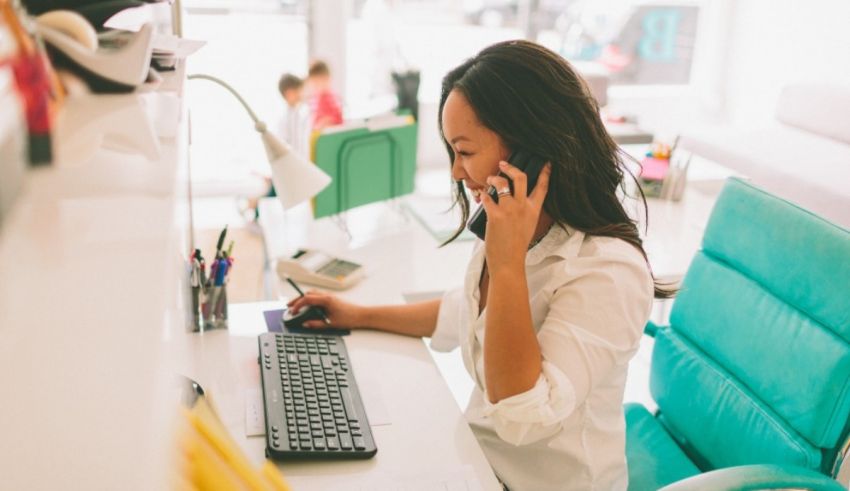 A woman talking on the phone while sitting at a desk.