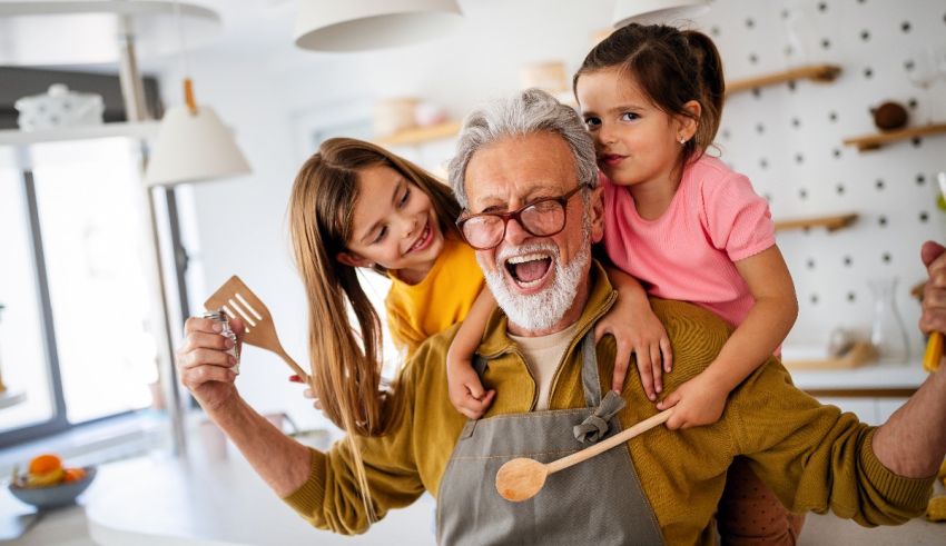 An old man and two little girls in the kitchen.