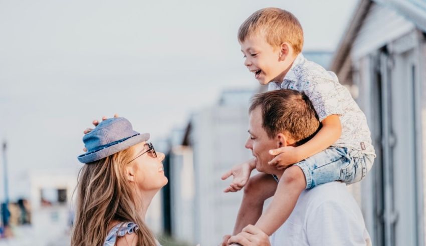 A man and woman holding a child on their shoulders at the beach.