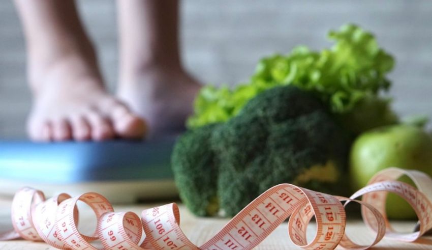 A measuring tape next to broccoli and lettuce.