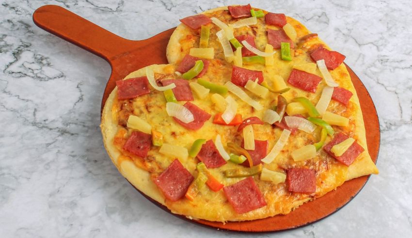 A heart shaped pizza on a wooden board.