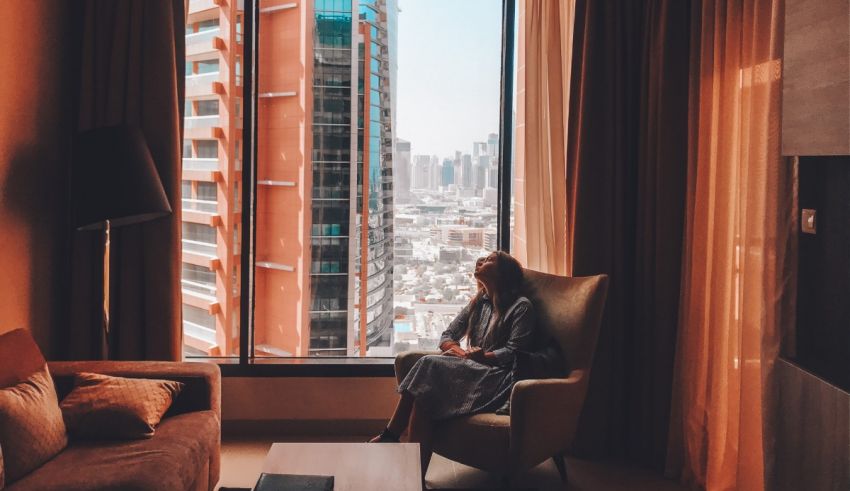 A woman sitting in a chair in front of a window overlooking a city.