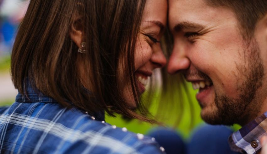 A man and woman are smiling at each other in a park.
