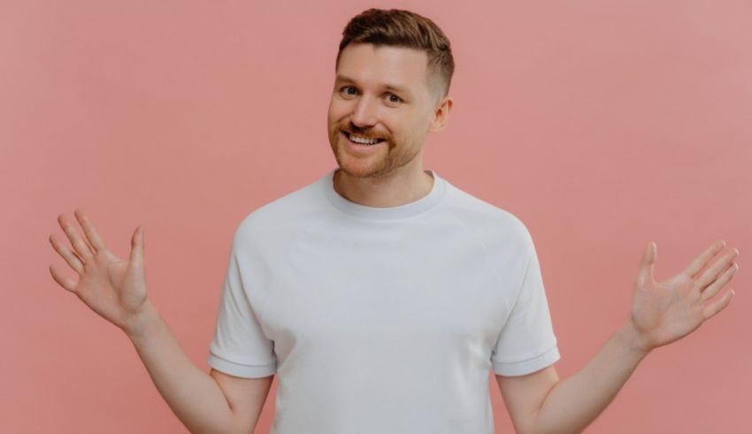 A man with his hands outstretched on a pink background.