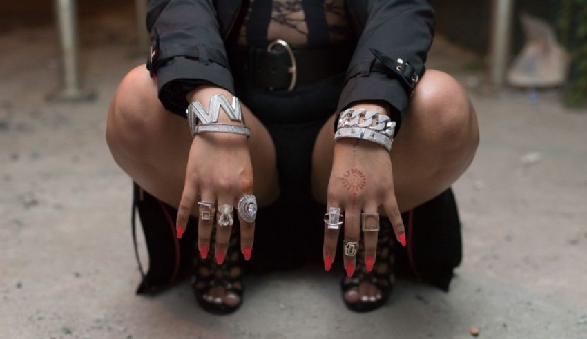 A woman crouching down with rings on her hands.