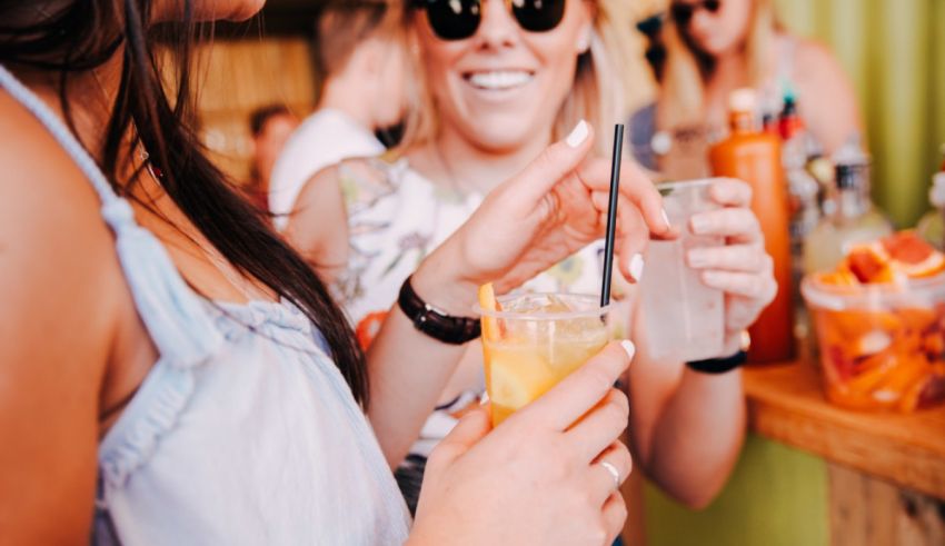 Two women are drinking drinks at an outdoor party.