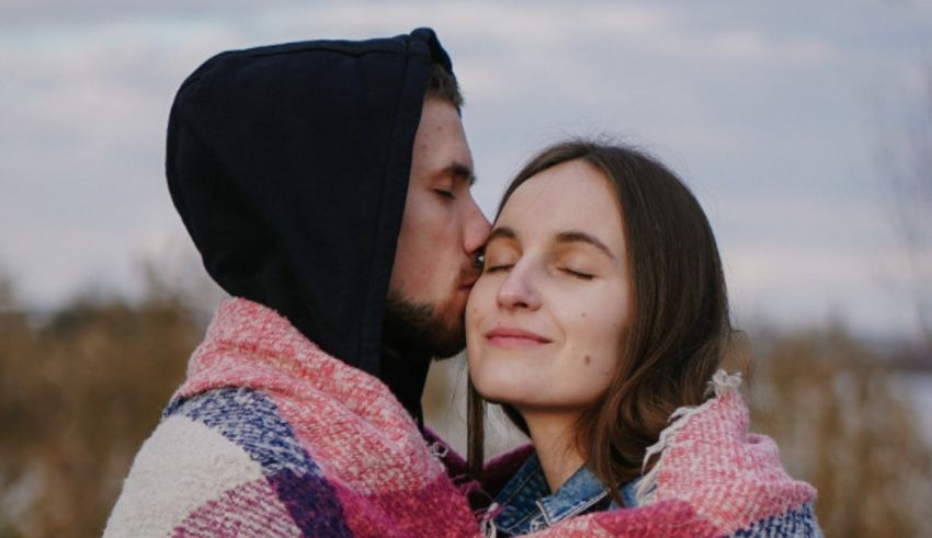 A man and woman are kissing in the field.
