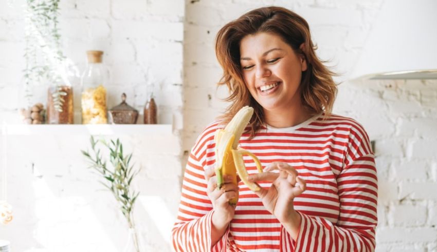A woman is eating a banana in the kitchen.