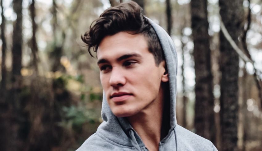 A man wearing a hoodie in the woods.