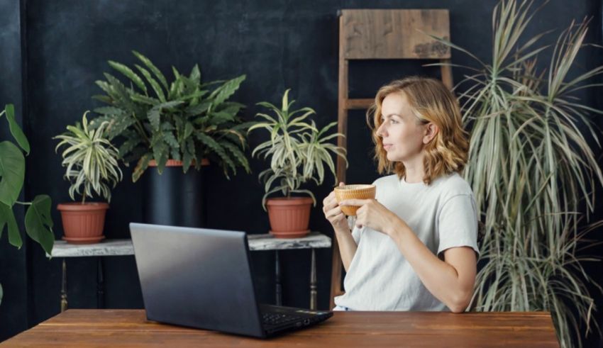 A woman sitting at a desk with a laptop and a cup of coffee.