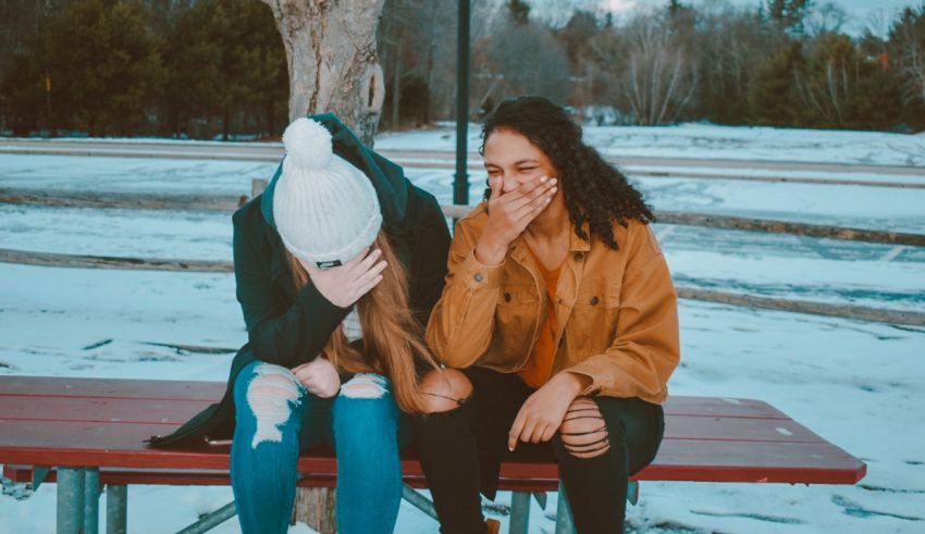Two girls sitting on a bench in the snow.