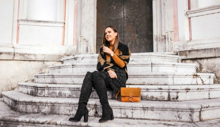 A woman sitting on the steps of a building holding a purse.