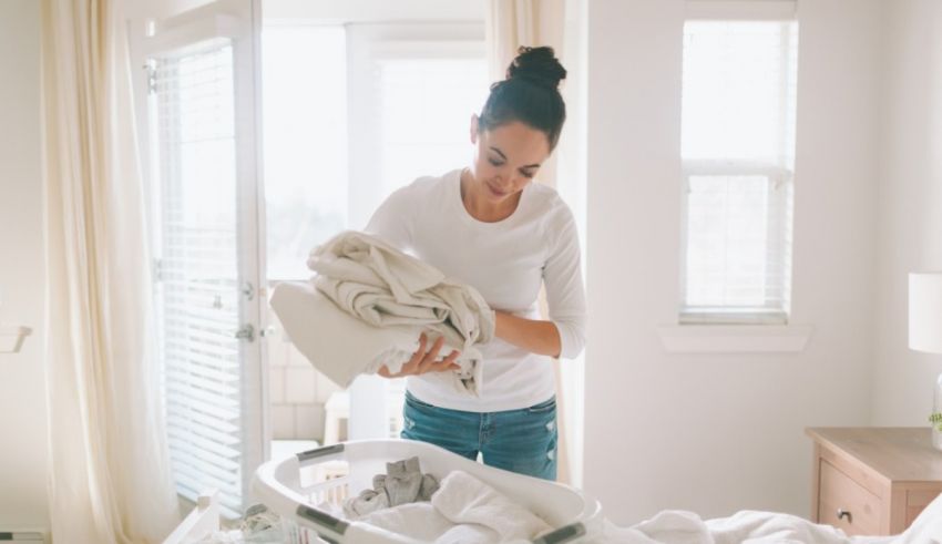 A woman is putting clothes on a bed.