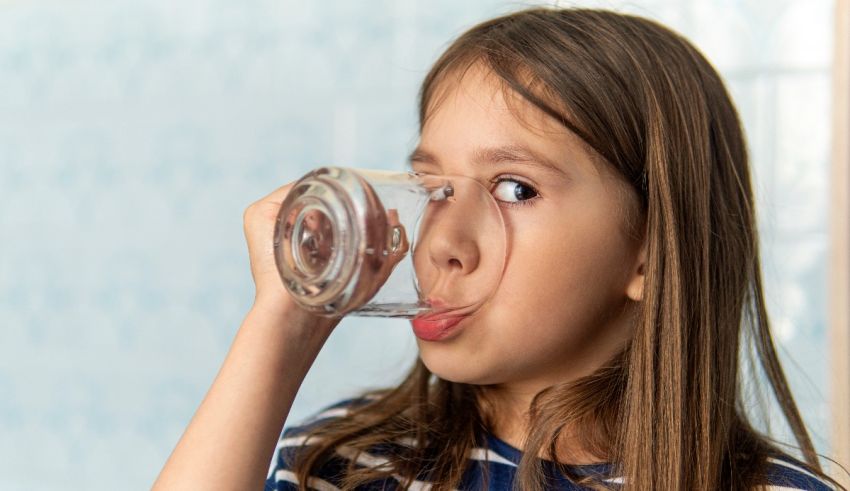 A little girl drinking water from a glass.