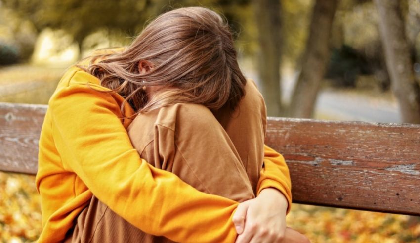 A woman is sitting on a bench in a park.