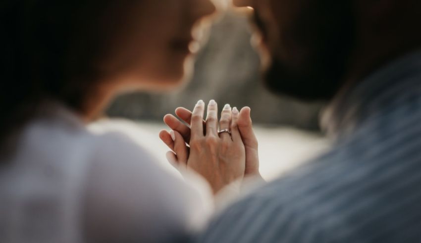 A man and woman are holding hands in front of a lake.