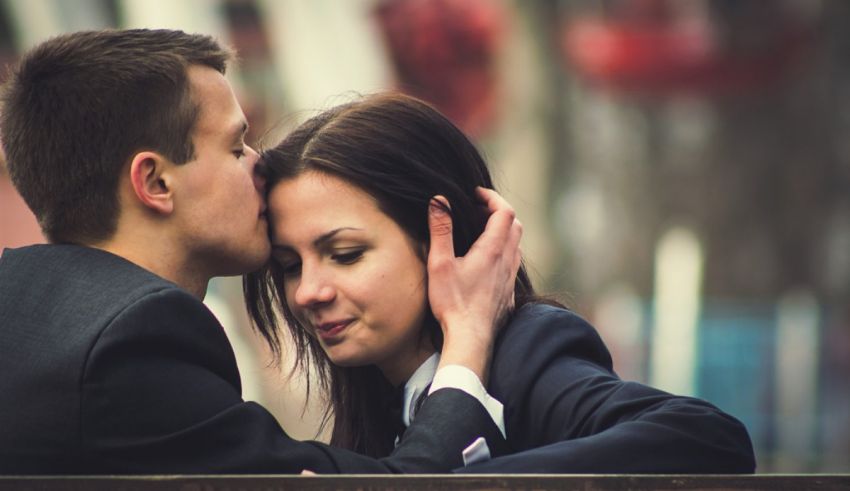 A man and woman kissing on a bench.