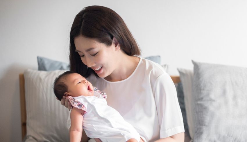 A woman is holding her baby on a bed.
